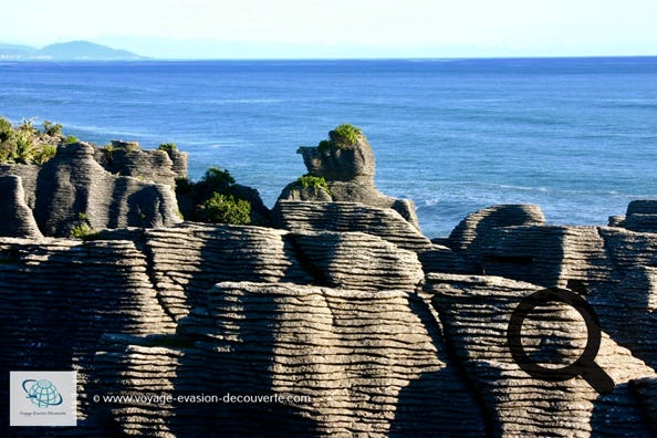 À Punakaiki face à la mer de Tasman se trouvent des formations géologiques étonnantes. C’est tout simplement superbe. Le littoral revêt l’extraordinaire apparence d’une série de millefeuilles pétrifiés. Des couches successives de calcaire érodé ont fini par former ces “Pancake Rocks“.
