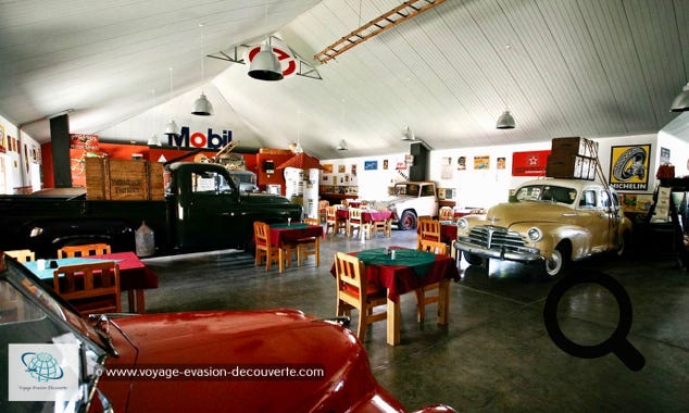 Il est hors du commun, ressemblant à un ancien relais routier au toit rouge, ce Lodge est un véritable trésor et un arrêt incontournable lors  de la visite de cette région. Dès que l’on arrive, on se retrouve projeté dans un monde extravagant avec des vieilles Chevys et Ford rouillées d'une époque révolue, sont éventrées par des arbres Carquois et de diverses plantes du désert.  Garez votre véhicule et entrez, le spectacle n’est pas fini… Comme si vous êtes entré dans un vieux garage du bout du monde, les grandes portes s'ouvrent sur un camion de transport servant de réception, un bar “pompstasie“ (station de pompage) et un assortiment de véhicules anciens et d'accessoires de transport assemblés décorant l’immense pièce. Les tables du restaurant sont placées entre des vieux véhicules comme une jeep, une ambulance, une ancienne voiture de police et beaucoup d’autres. Ambiance et dépaysement assuré…